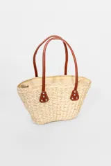Bolso playero tipo tote de paja color beige con asas de cuero marrón.