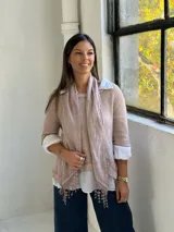 Sweater de punto rosa claro con diseño de capas, que incluye una camisa blanca debajo y un pañuelo a juego con detalles de encaje y flecos en el ruedo.
