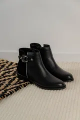 Botas cortas de cuero negro con paneles traseros de gamuza, cierre lateral y detalle de correa con hebilla metálica en el tobillo.