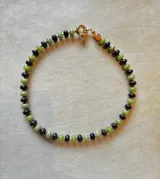 Collar de piedras naturales de calcedonia pulida en tonos verdes y granates, con detalle central de cristal de Murano y cierre tipo marinero con baño de oro 18k.