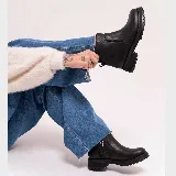 Bota corta de cuero vacuno color negro, con suela de goma tipo track y cierre lateral interno. Presenta punta redonda y diseño minimalista.
