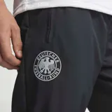 Pantalón deportivo adidas Alemania 1994 de color negro, con cintura elástica con cordón ajustable, bolsillos laterales con cierre y puños elásticos en los tobillos. Presenta detalles de la selección alemana y de la marca.