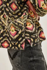 Sweater de punto con cuello redondo y manga larga, estampado en tonos oscuros con motivos geométricos y florales en rosa, amarillo y verde.