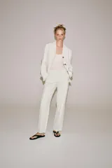 Pantalón ZARA Woman Collection de tiro medio y corte recto, confeccionado en hilatura con mezcla de lino en color blanco. Cuenta con cintura con trabillas, bolsillos laterales ocultos en costura, detalle de raya planchada y cierre frontal con cremallera, botón y ganchos metálicos.