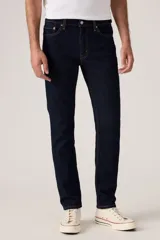 Jean de corte slim fit en color azul oscuro, con diseño clásico de cinco bolsillos, cierre de cremallera y botón metálico.