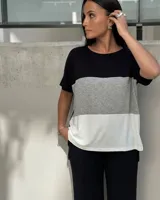 Remera de corte holgado con diseño tricolor en bloques horizontales de color negro, beige y blanco. Presenta cuello redondo, mangas cortas y un diseño de largo asimétrico con tajos laterales.