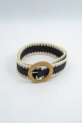 Cinturón de tejido elástico en color negro con bordes en color crema y hebilla circular de madera.