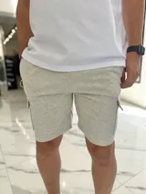 Bermuda cargo de jogging color gris melange, con bolsillos laterales con solapa y cordón ajustable en la cintura.