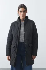 Campera capitoneada de largo medio, color negro, con cuello alto, cierre frontal con cremallera y broches a presión, y bolsillos laterales con solapa.