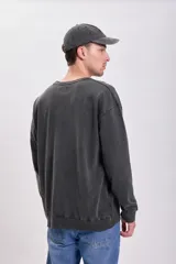 Buzo de cuello redondo en color negro con efecto lavado, de corte holgado y mangas largas con puños acanalados.