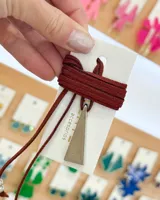 Gargantilla con cordón de gamuza marrón y dije triangular plateado.