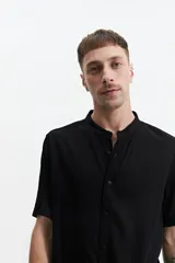 Camisa negra de manga corta con cuello mao y doblez en las mangas.