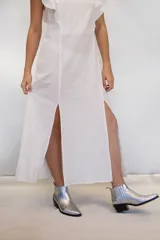 Vestido largo de algodón tusor en color blanco, con volados en las sisas que simulan mangas y aberturas laterales en la falda.