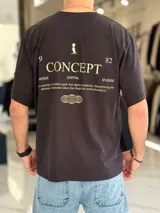 Remera oversize color negro con diseño gráfico estampado en la espalda en tono dorado, con la inscripción 'Concept' y detalles tipográficos.