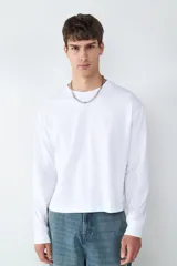 Camiseta de manga larga con corte boxy y cuello redondo, confeccionada en 100% algodón. Presenta una silueta holgada y diseño minimalista.