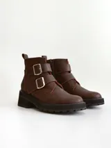 Botas cortas de cuero color marrón con suela track negra. Presentan dos correas ajustables con hebillas metálicas plateadas en el empeine y cierre lateral interno.