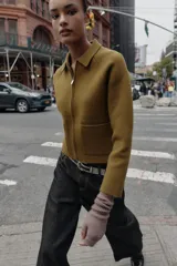 Chaqueta de punto de corte recto, color verde oliva, con cuello solapa, cierre frontal con cremallera y bolsillos delanteros de plastrón.