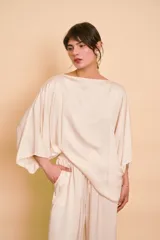 Blusa de satén color beige, con escote bote, corte holgado y mangas amplias tipo kimono.
