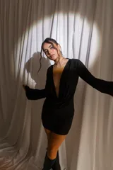 Vestido corto negro de tul y lycra, con escote en V profundo drapeado, mangas largas acampanadas y corte ajustado.