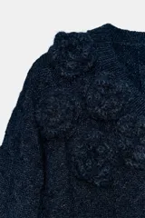 Jersey de punto color azul marino con escote en pico y manga larga. Presenta un diseño texturizado con aplicaciones de flores en relieve del mismo tejido en el cuello y el ruedo.