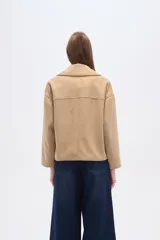 Chaqueta corta estilo peacoat, color beige, con cuello solapa y cierre cruzado de doble botonadura. Presenta un calce holgado y bolsillos laterales.