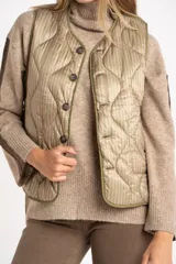 Chaleco capitoneado color verde oliva, con cierre frontal de botones, cuello redondo y diseño acolchado con costuras onduladas.