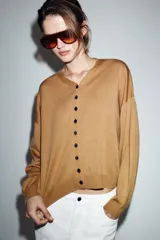 Chaqueta de punto color tostado con cuello en pico, manga larga con puños y cierre frontal con botones.