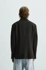 Blazer azul marino de corte recto, confeccionada en tejido con viscosa. Tiene cuello con solapas de muesca, manga larga con puño abotonado, bolsillo de vivo en el pecho y bolsillos de parche en la cadera. El bajo tiene aberturas en la espalda y el cierre es con botonadura frontal.