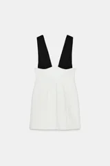 Vestido corto bicolor con cuerpo blanco y tirantes anchos negros plisados en contraste, de escote en pico y corte ajustado.