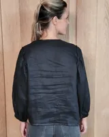 Camisa de manga larga con diseño de rayas verticales y bordados sutiles. Presenta cuello redondo, cierre frontal con botones y mangas abullonadas con volados en los hombros.