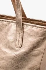 Bolso tipo tote bag color dorado con efecto arrugado y dos asas superiores.