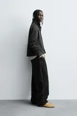 Sobrecamisa negra de algodón con estructura canvas, corte cropped y calce holgado. Presenta cuello solapa, manga larga, bolsillos laterales en cadera y cierre frontal con botones a presión metálicos.