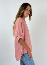 Camisa color salmón de lino, de corte recto, con cuello clásico, cierre frontal con botones y mangas 3/4 con trabilla.