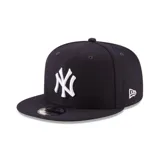 Gorra New Era modelo 9FIFTY con visera plana, color negro con el logotipo de los New York Yankees bordado en relieve en color blanco en la parte frontal.