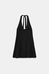 Vestido corto negro con cuello halter, escote en pico y falda con vuelo. Cuenta con tirantes para anudar al cuello y costuras visibles en el cuerpo.