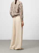 Jersey de punto con cuello en pico y manga larga, confeccionado en tejido jacquard con diseño abstracto. Presenta terminaciones en canalé en puños y cintura, ofreciendo una textura suave y ligera.