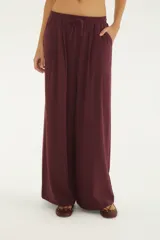 Pantalón ancho bordó de talle alto con cintura elástica fruncida y cordón ajustable del mismo tejido, bolsillos laterales y caída fluida.