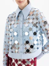 Camisa de manga larga confeccionada en guipur con apliques de espejos circulares. Presenta cuello clásico, puños y cartera de botones a presión forrados al tono. Incluye top interno al tono.