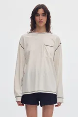 Remera de manga larga negra con bolsillo frontal en el pecho y costuras a la vista en contraste de color gris.