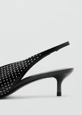 Zapato destalonado negro de tacón fino bajo, con punta fina y toda la superficie decorada con tachas plateadas pequeñas.