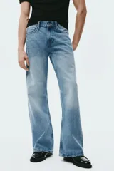 Jean de cinco bolsillos en denim de algodón rígido, con cintura estándar, cierre y botón. Corte relajado y piernas levemente acampanadas con efecto desgastado en los muslos.