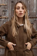 Gabardina liviana color beige con capucha, cierre frontal oculto y cintura ajustable mediante cordón. Presenta bolsillos delanteros amplios y mangas largas con puños rectos.