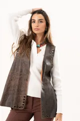 Chaleco de cuero marrón con silueta relajada, caracterizado por detalles de ojalillos metálicos a lo largo de los bordes frontales.