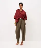 Pantalón de sintonía sastrera corte barrel color verde militar, de diseño estructurado con volumen suave en las piernas y terminación afinada. Cuenta con cintura con pasacintos, pinzas delanteras, bolsillos laterales y cinturón desmontable con hebilla metálica.