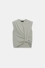 Top de punto negro con cuello redondo, manga sisa, hombreras y detalle de pliegues en la parte delantera.