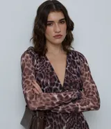 Vestido midi de manga larga confeccionado en tule con estampado animal print. Presenta un escote en V profundo, corte ajustado al cuerpo y diseño con transparencia.