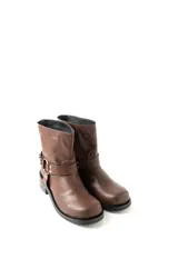 Botas de caña baja en ecocuero color marrón, con diseño de estilo western que incluye una tira decorativa con hebilla metálica y remaches en el lateral. Poseen una base plana con un pequeño taco cuadrado y costuras reforzadas.