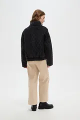 Campera de estilo bomber con diseño capitoneado en forma de rombos, color negro con efecto lavado. Presenta cuello alto, cierre frontal metálico y bolsillos laterales.