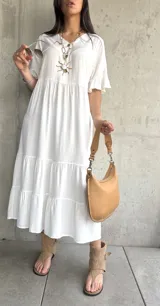 Vestido midi blanco con corte en capas, mangas cortas con volados y cuello redondo.