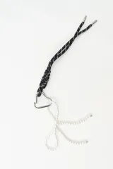 Llavero con cordón trenzado negro con detalles plateados, mosquetón metálico en forma de corazón y colgante en forma de lazo hecho con perlas sintéticas.